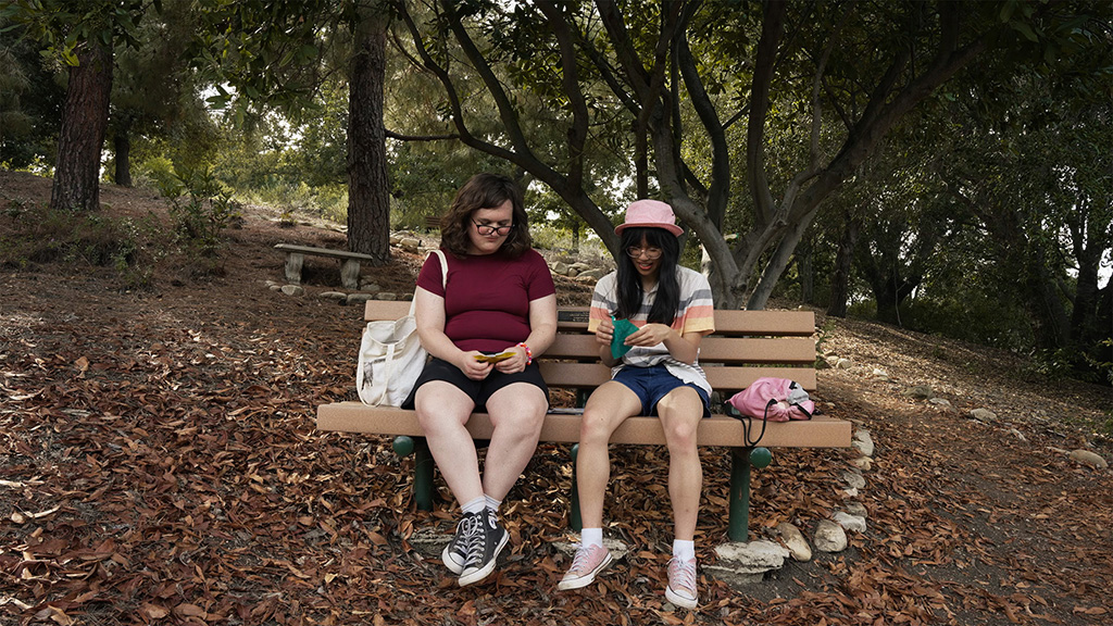 Two people sitting on a bench in a park